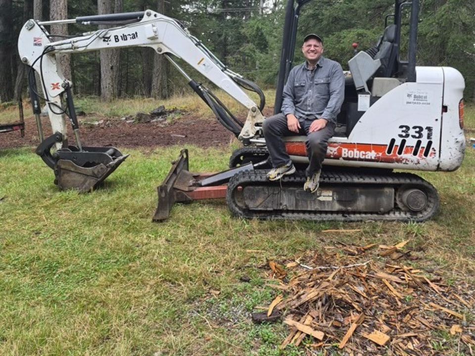 Joe sitting on his Bobcat mini-excavator at a job site